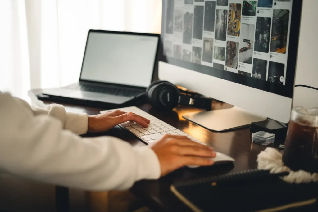 Designer using a desktop computer and laptop to create a custom website design