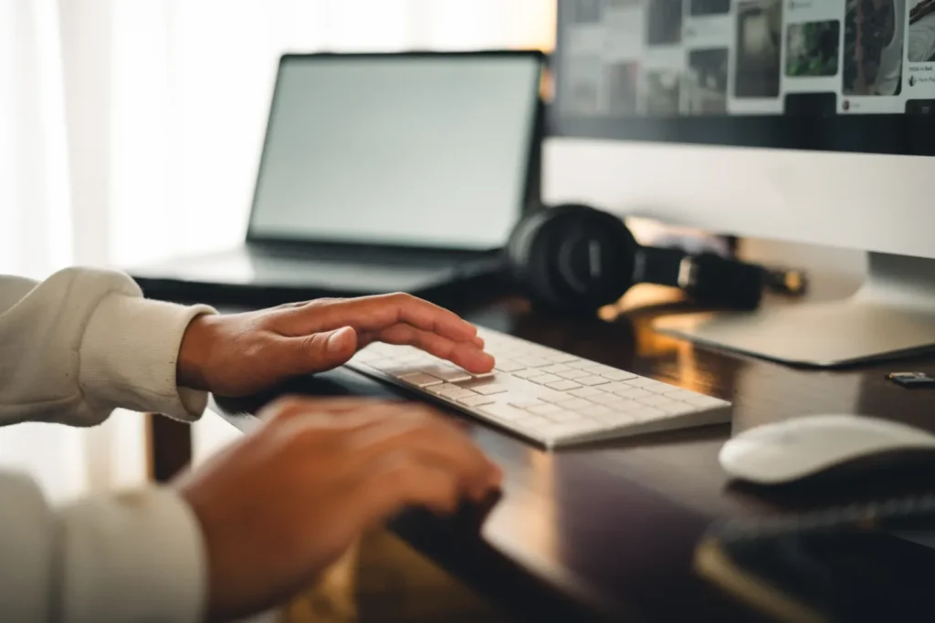 Person managing an online store on a desktop computer with a laptop nearby