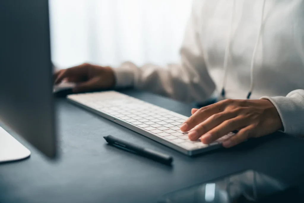 Hands typing on a keyboard while updating a website on a desktop computer